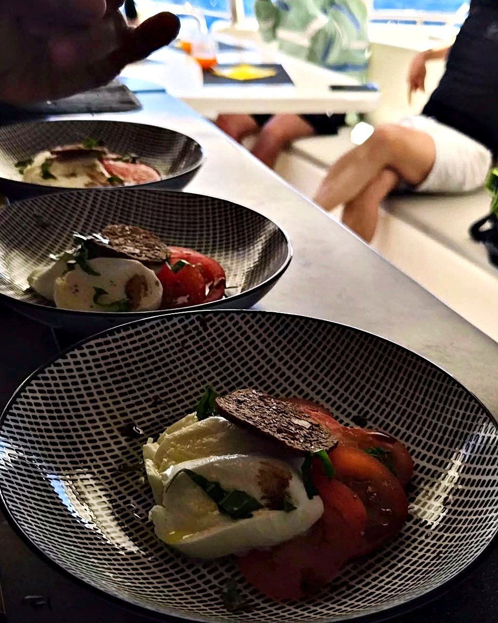 Trois assiettes sur le comptoir d’un catamaran, la mer derrière